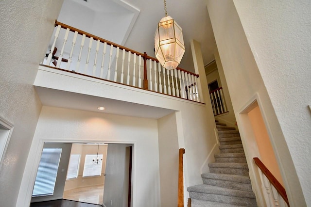 stairs with a textured wall and a towering ceiling