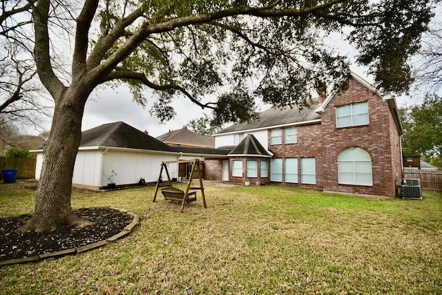 back of house featuring brick siding, fence, cooling unit, and a yard