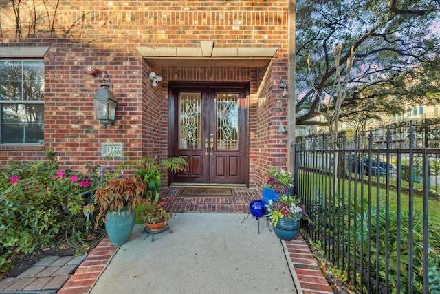 entrance to property with fence, french doors, and brick siding