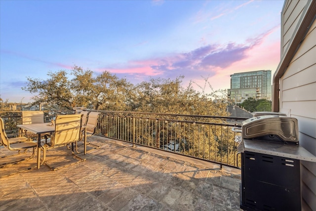 patio terrace at dusk featuring outdoor dining space and a grill