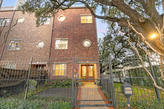 view of front of house with a fenced front yard, a gate, and brick siding