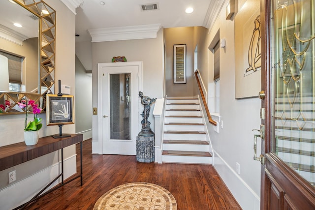 foyer featuring baseboards, visible vents, ornamental molding, wood finished floors, and stairs