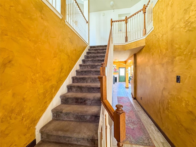 staircase with arched walkways and a towering ceiling