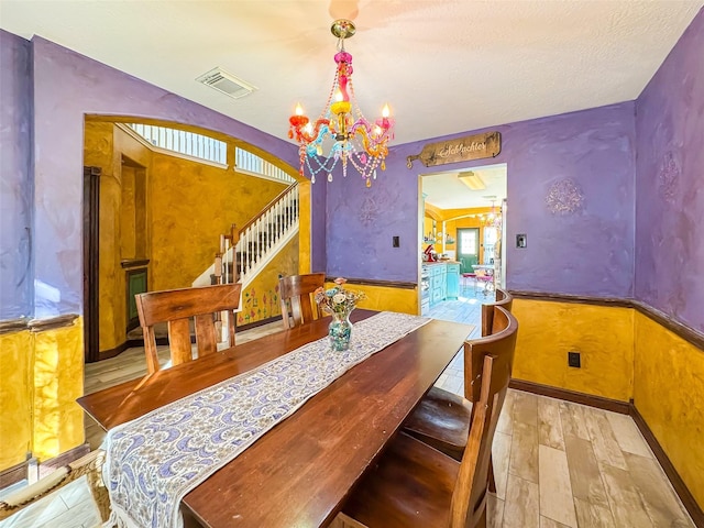 dining room with visible vents, stairs, a chandelier, and wainscoting