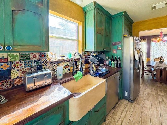 kitchen with visible vents, dark countertops, stainless steel appliances, green cabinets, and a notable chandelier