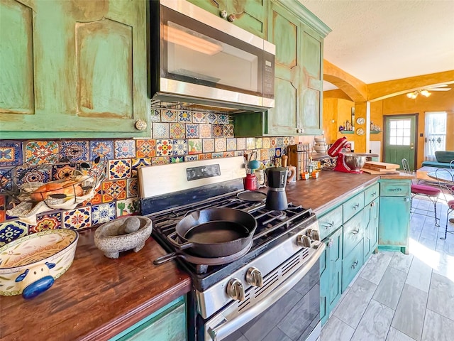 kitchen featuring tasteful backsplash, wood counters, appliances with stainless steel finishes, open floor plan, and green cabinetry