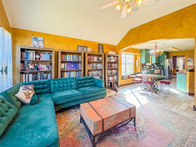 living area with ceiling fan, light wood-style flooring, arched walkways, and vaulted ceiling