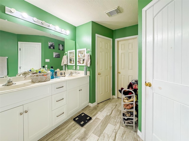 bathroom with wood finished floors, a sink, visible vents, a closet, and double vanity