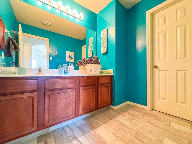 bathroom featuring baseboards, visible vents, wood finished floors, and vanity