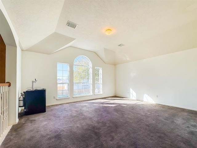 carpeted spare room with lofted ceiling, visible vents, a textured ceiling, and baseboards