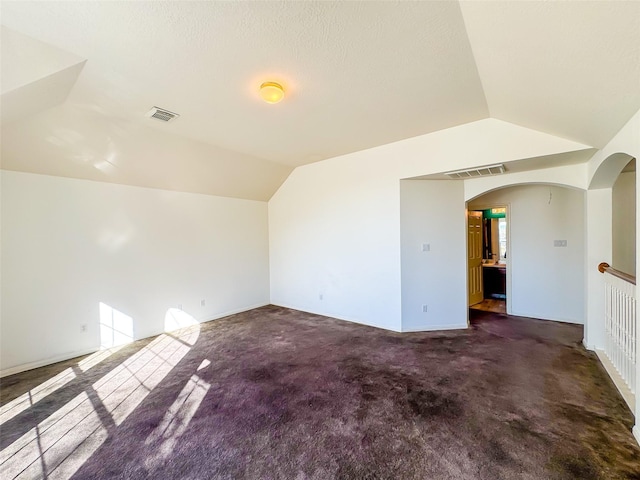 bonus room featuring carpet floors, lofted ceiling, visible vents, and arched walkways