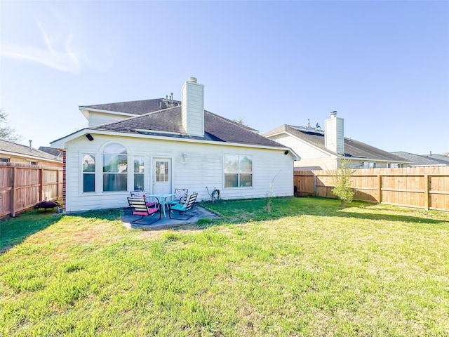 back of property featuring a yard, a chimney, a patio area, and a fenced backyard