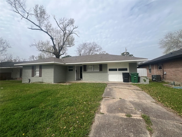 single story home featuring brick siding, an attached garage, a front yard, central AC, and driveway