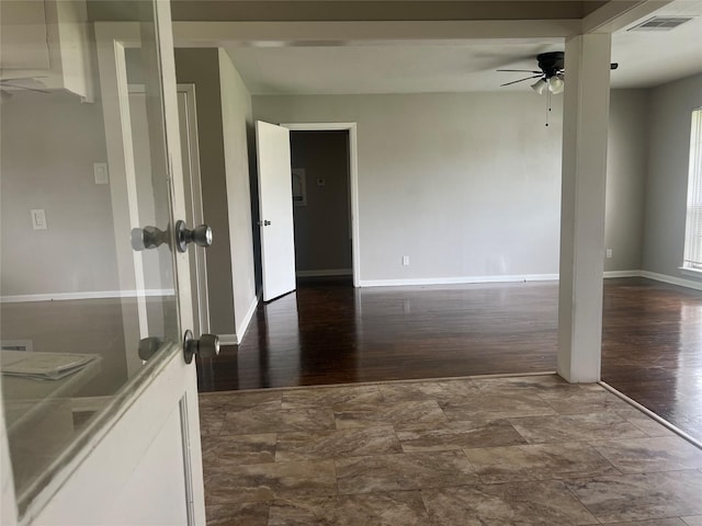 empty room with ceiling fan, dark wood-style floors, visible vents, and baseboards