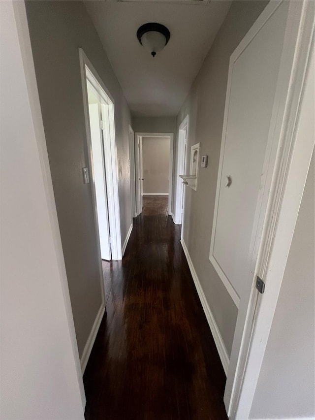 hallway featuring baseboards and wood finished floors