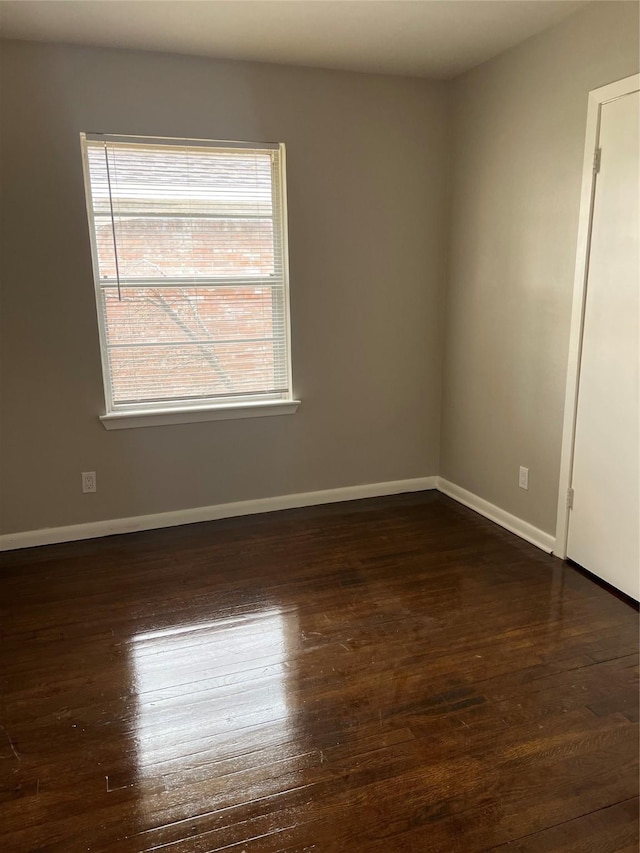 spare room featuring dark wood-style floors and baseboards