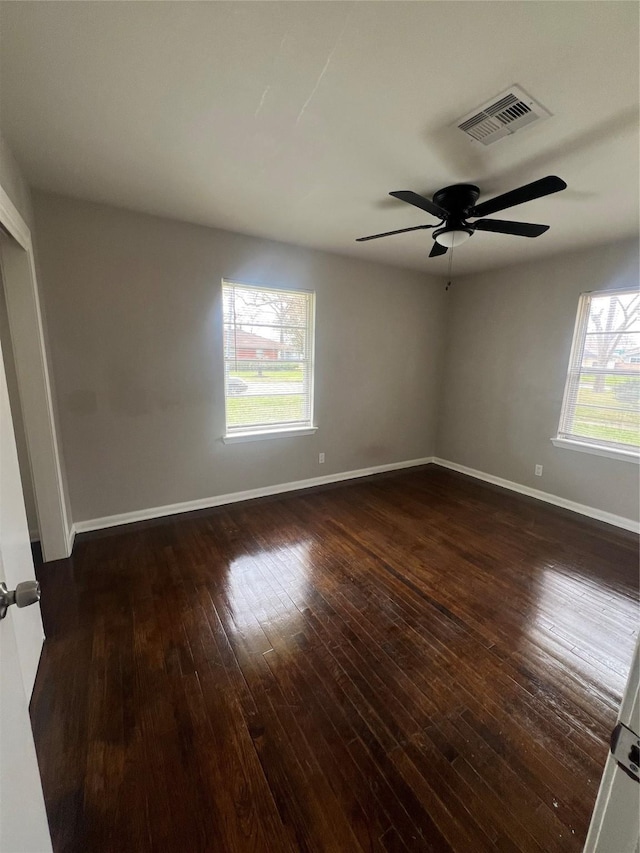 spare room with ceiling fan, wood-type flooring, visible vents, and baseboards