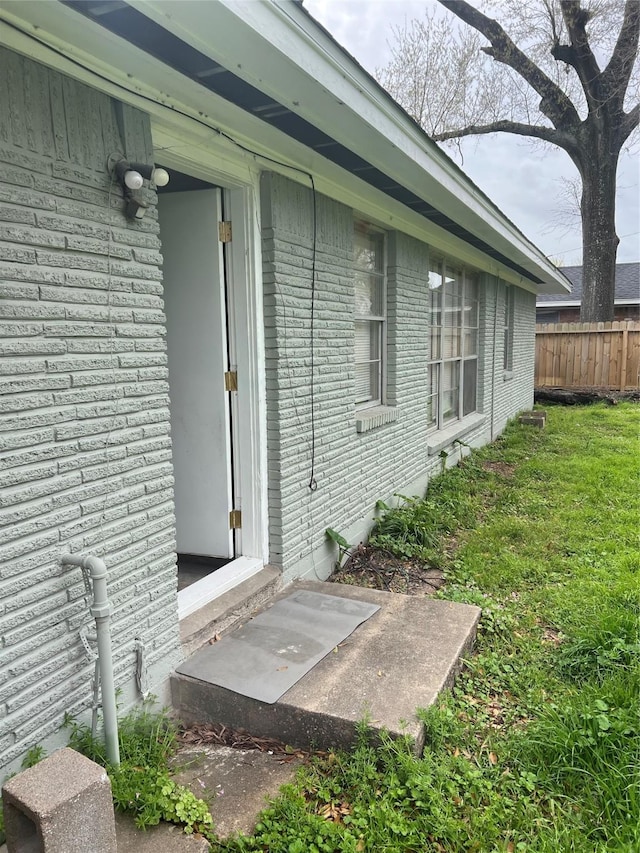 view of side of home featuring a yard, brick siding, and fence