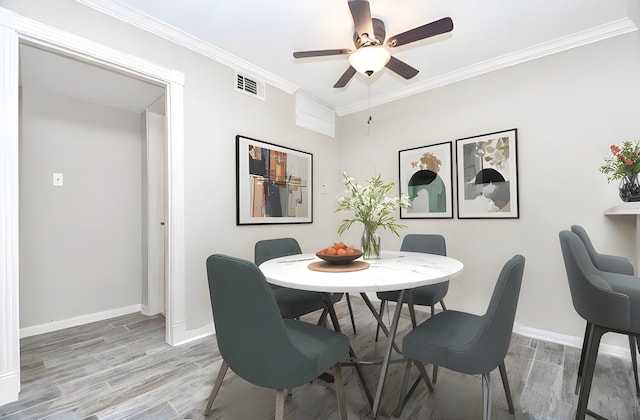 dining area with baseboards, light wood finished floors, visible vents, and crown molding