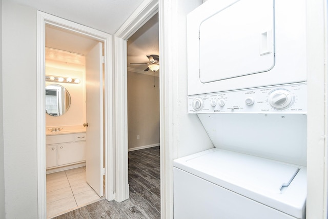 washroom featuring stacked washer and dryer, laundry area, light wood finished floors, a ceiling fan, and a sink