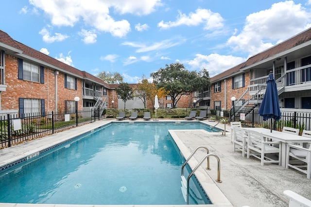 community pool with a residential view, a patio area, and fence