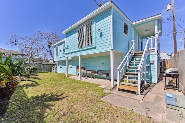 rear view of house with a patio area, a fenced backyard, stairway, and a yard