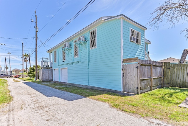 view of side of home featuring a garage, driveway, and fence