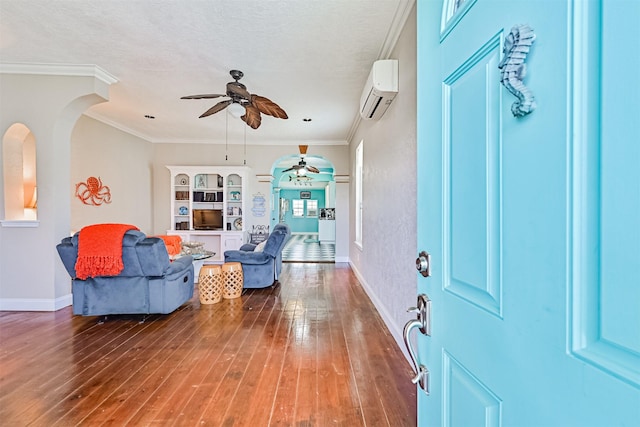 entryway featuring baseboards, hardwood / wood-style flooring, ornamental molding, a wall mounted air conditioner, and a textured ceiling