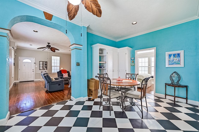 dining room with arched walkways, tile patterned floors, a ceiling fan, and a healthy amount of sunlight