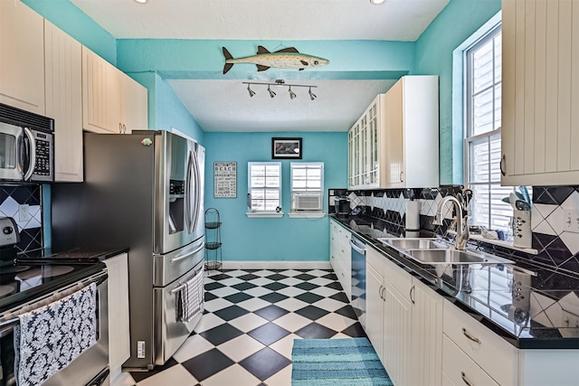 kitchen with appliances with stainless steel finishes, dark countertops, a sink, and light floors