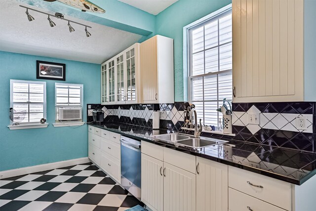 kitchen with dishwashing machine, a sink, tile patterned floors, dark countertops, and plenty of natural light