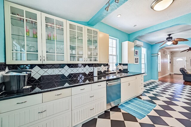 kitchen with arched walkways, dark floors, dark countertops, a wall mounted AC, and dishwashing machine