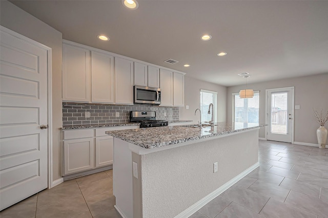 kitchen with light tile patterned flooring, stainless steel appliances, a sink, visible vents, and backsplash