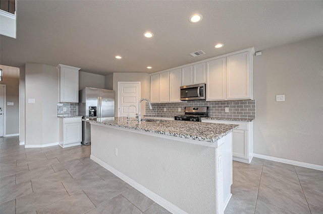 kitchen with light tile patterned floors, visible vents, light stone counters, stainless steel appliances, and a sink