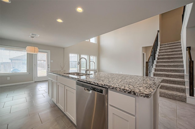 kitchen with light stone counters, light tile patterned flooring, a sink, and stainless steel dishwasher