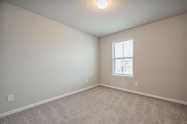 spare room with light colored carpet and baseboards