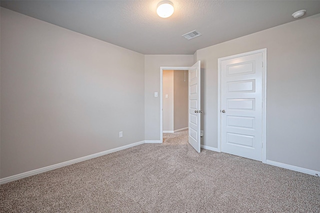 unfurnished bedroom featuring baseboards, a textured ceiling, visible vents, and light colored carpet