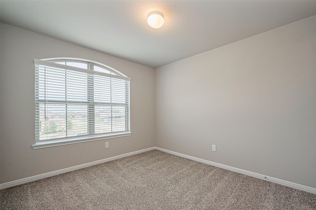 empty room featuring carpet and baseboards