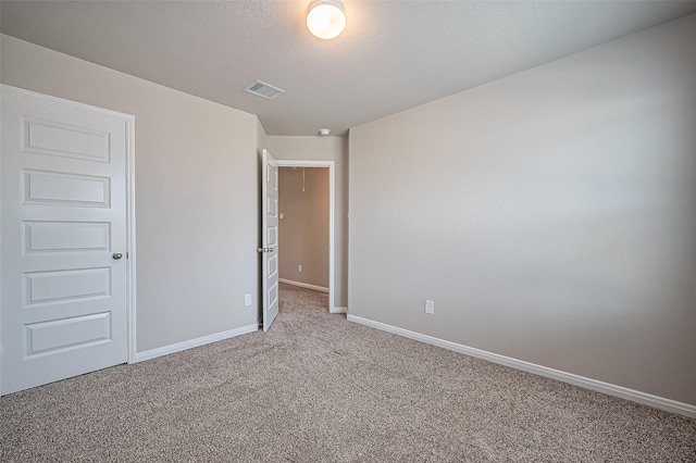 unfurnished room featuring baseboards, a textured ceiling, visible vents, and carpet flooring