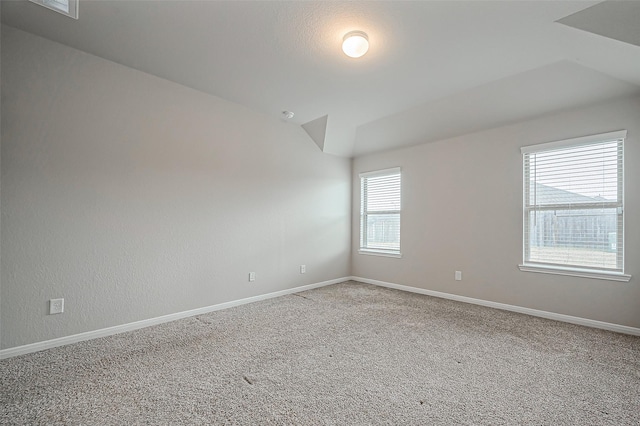 carpeted empty room with vaulted ceiling and baseboards