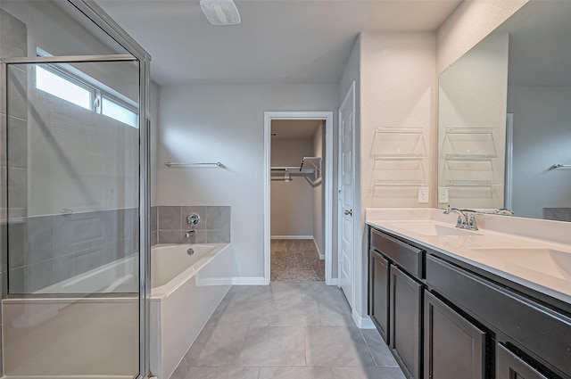 bathroom with a garden tub, a spacious closet, a stall shower, a sink, and tile patterned floors