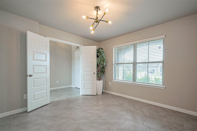 empty room with baseboards, light tile patterned floors, and a notable chandelier