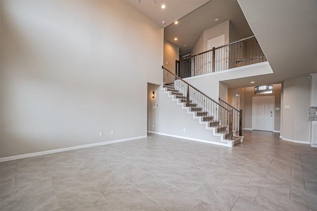 interior space with a towering ceiling, stairs, baseboards, and recessed lighting