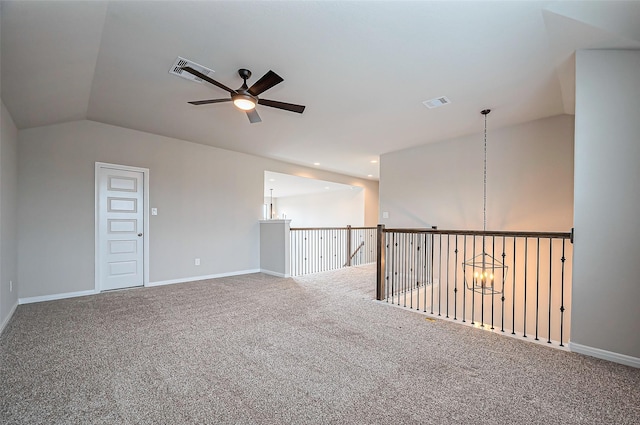 carpeted empty room with visible vents, vaulted ceiling, and baseboards