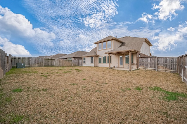 rear view of house featuring a fenced backyard, a patio, and a yard