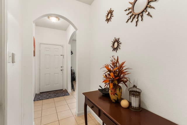 doorway to outside featuring light tile patterned floors, baseboards, and arched walkways