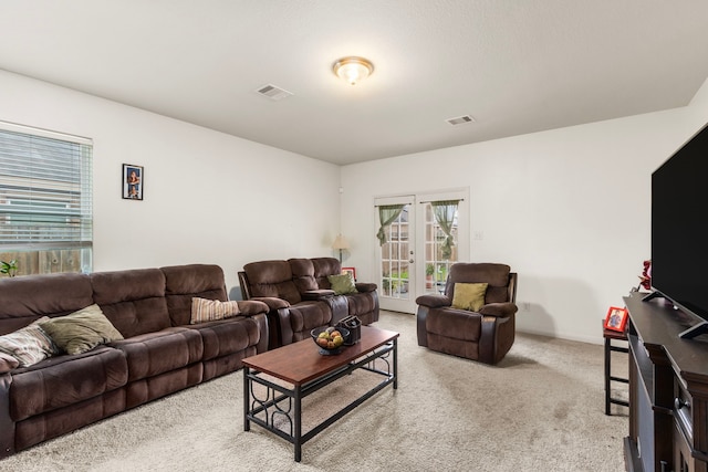 carpeted living room with baseboards, visible vents, and french doors