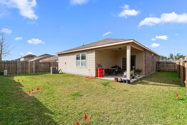 rear view of house with a patio, central AC unit, a fenced backyard, brick siding, and a yard