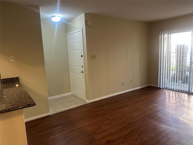 interior space featuring a textured ceiling, wood finished floors, and baseboards