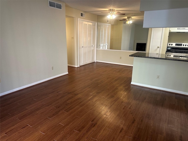 unfurnished living room with baseboards, visible vents, dark wood finished floors, and a ceiling fan